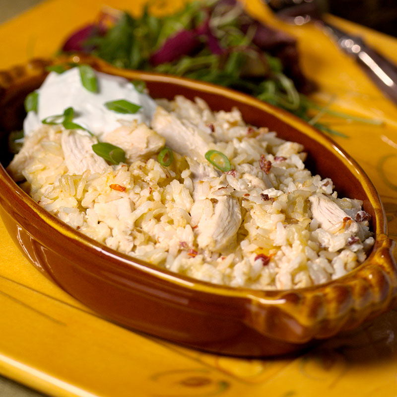 Side view of smokey mountain chicken and rice casserole in a brown ceramic serving dish.