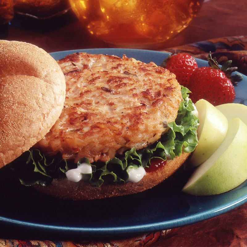 Side view of rice smorgasburger on a blue plate with apple slices and strawberries.