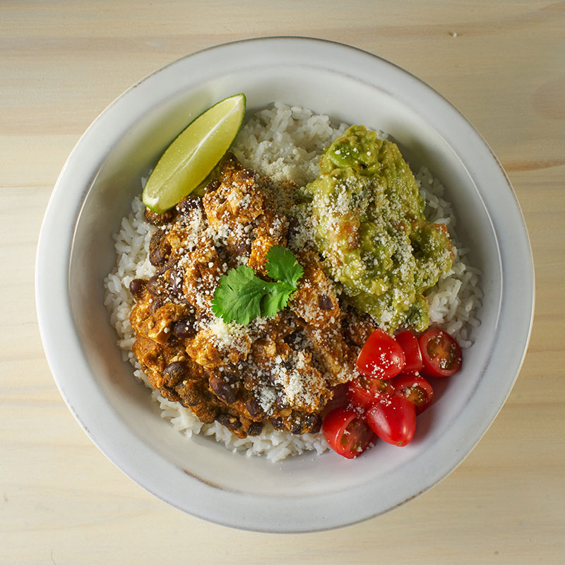 Overhead view of sofritas rice bowl on a wooden countertop. 