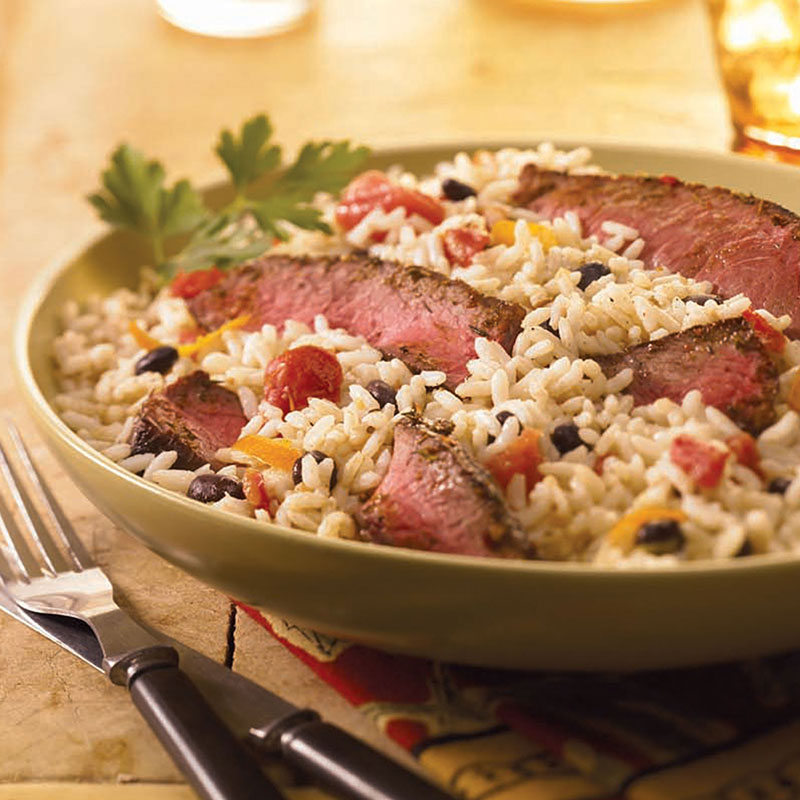 Southwestern Steak Rice and Black Beans Side view of southwestern steak, rice, and black beans in a tan bowl.