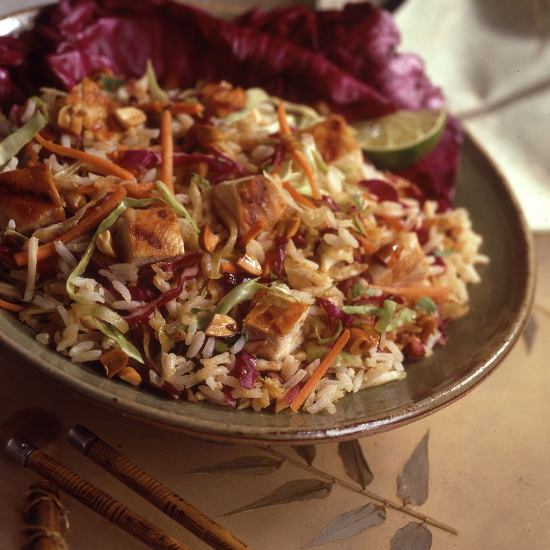 Image of a large serving of Spicy Thai Chicken Salad on a dark green plate garnished with lime wedges.