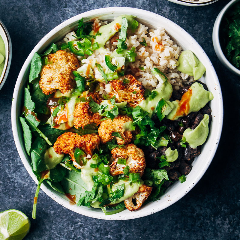 Overhead image of a Spicy Vegan Burrito Bowl with Chipotle Cauliflower on top.