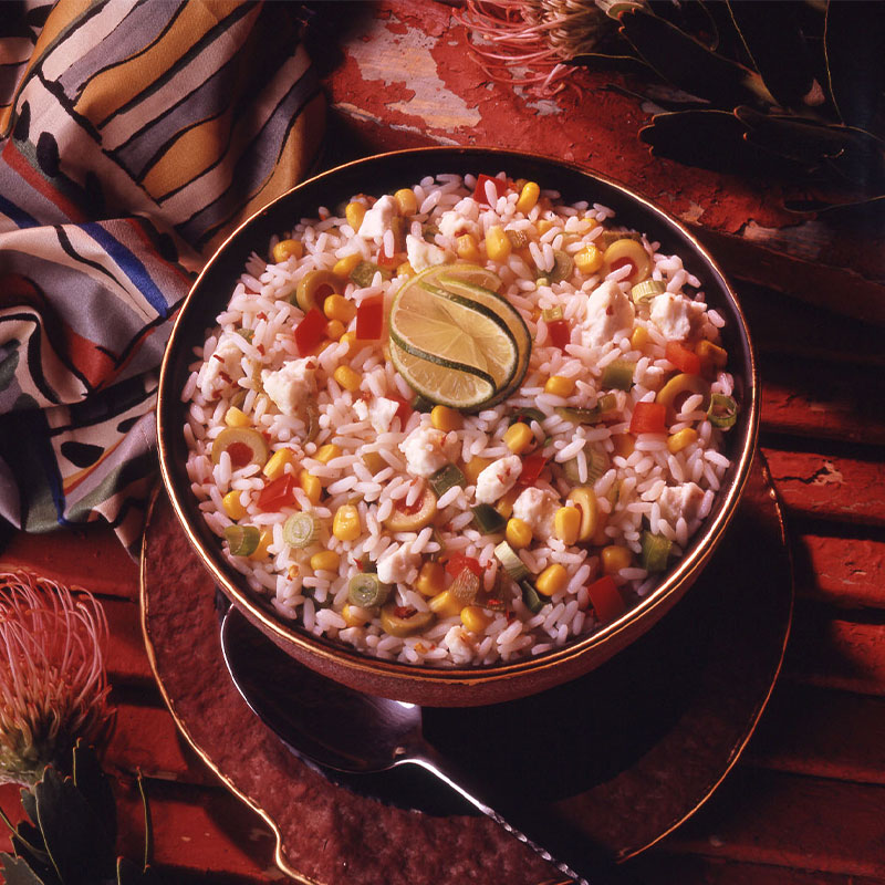 Overhead shot of white rice filled with colorful vegetable pieces with a lime wedge on top.