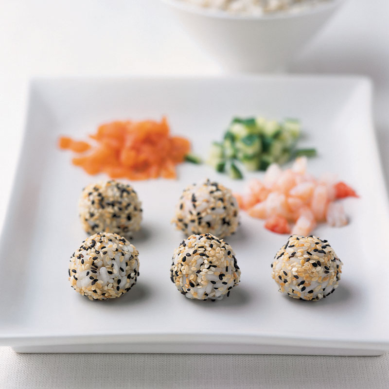 A white plate with five made sushi poppers with popper content in the distance.