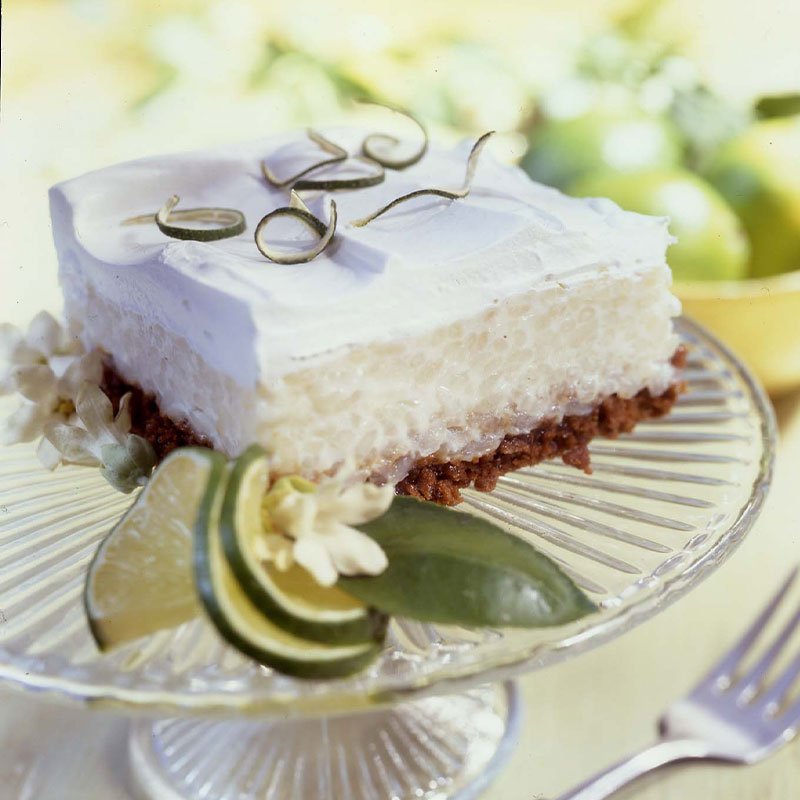 Tangy Lime Rice Pudding Squares One Tangy Lime Rice Pudding Squares topped with whipped cream on a small plate.