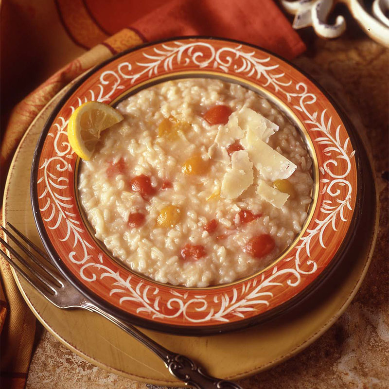 Overhead image of Tangy Tomato and Lemon Risotto topped with parmesan in a bowl.