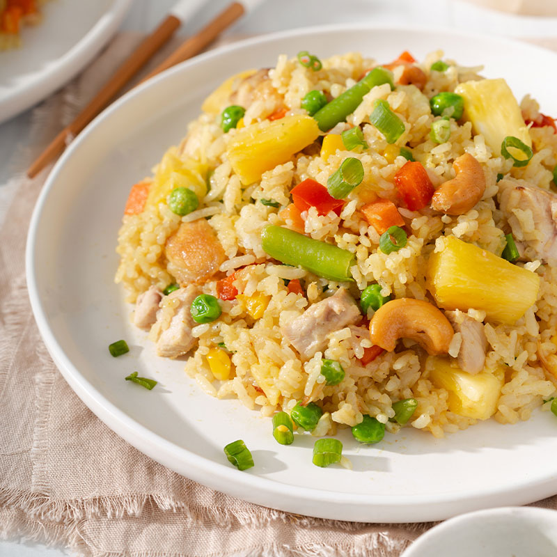 Side shot of a serving of Thai Pineapple Fried Rice on a white plate.