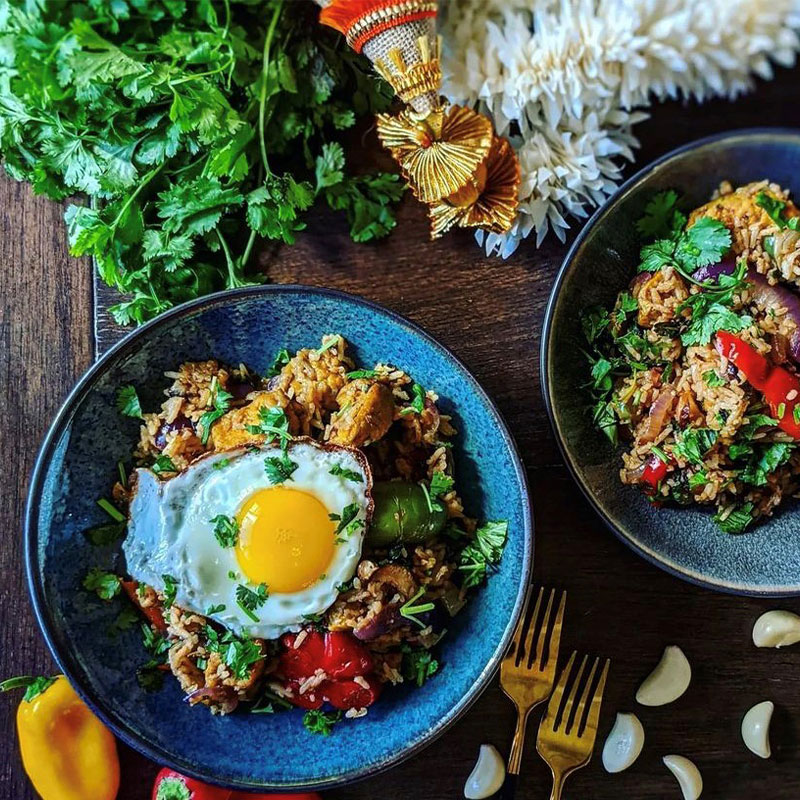 Overhead view of two bowls of Tom Yum Fried Rice topped with a fried egg.