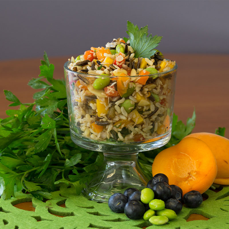 A transparent cup filled with tropical wild rice medley salad. 