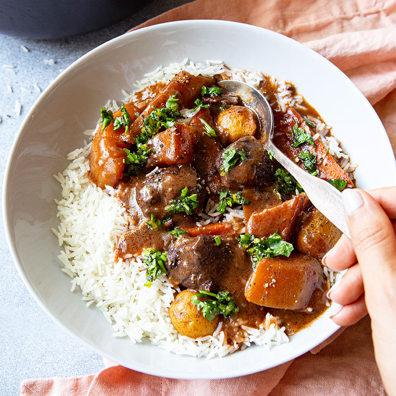 A bowl of Vegetable & Beef Stew served over rice.