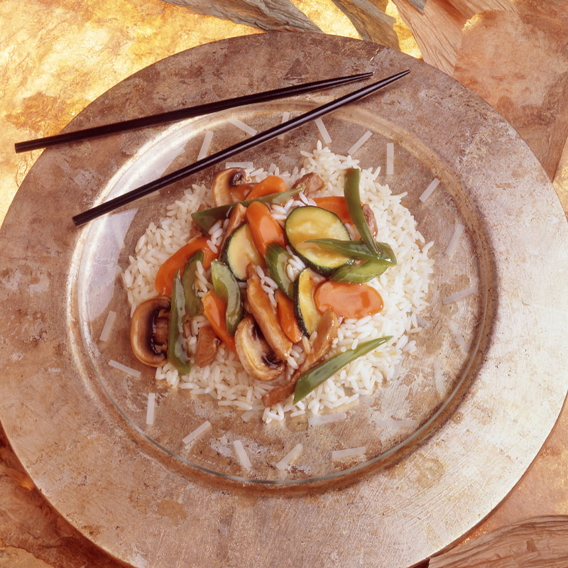 Overhead image of a brown plate with Vegetable Pork Stir-Fry on a bed of white rice.