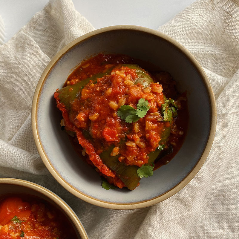 Overhead shot of a large green stuffed pepper covered in tomato sauce.