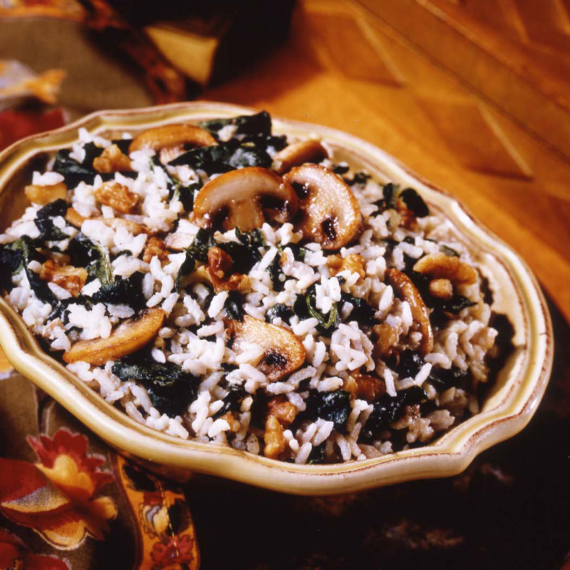 Side view of a bowl of Walnut Rice with cream cheese that has spinach and mushrooms exposed.