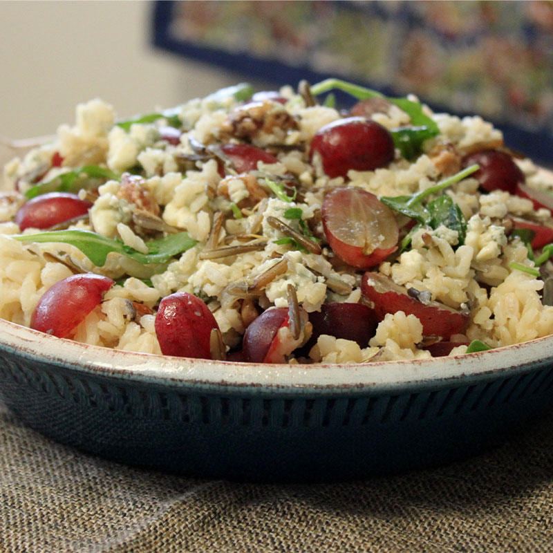Side view of a wild and brown rice bowl topped with roasted red grapes.