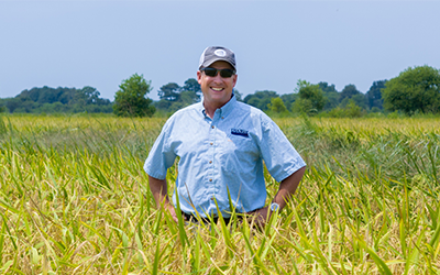 Kane Webb stands in a rice field