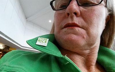 Deborah Willenborg shows off Think Rice pin on green jacket lapel