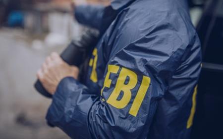 Person wearing jacket with FBI in yellow on sleeve