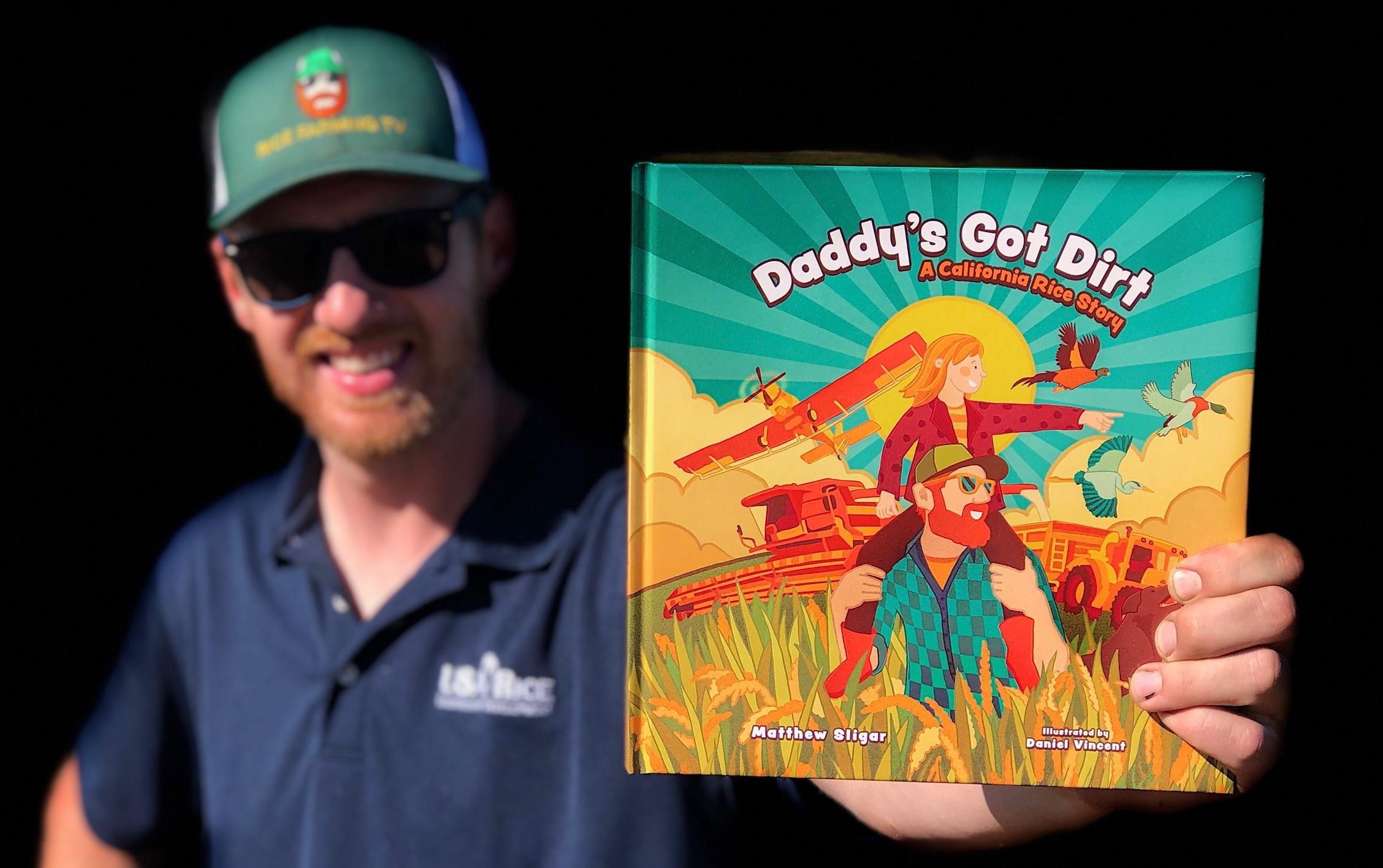 White man wearing ballcap holds childrens book, Daddy