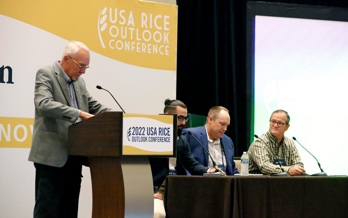 Organics-Panel-at-Outlook on stage, one man at podium, three others seated at a table w/microphones