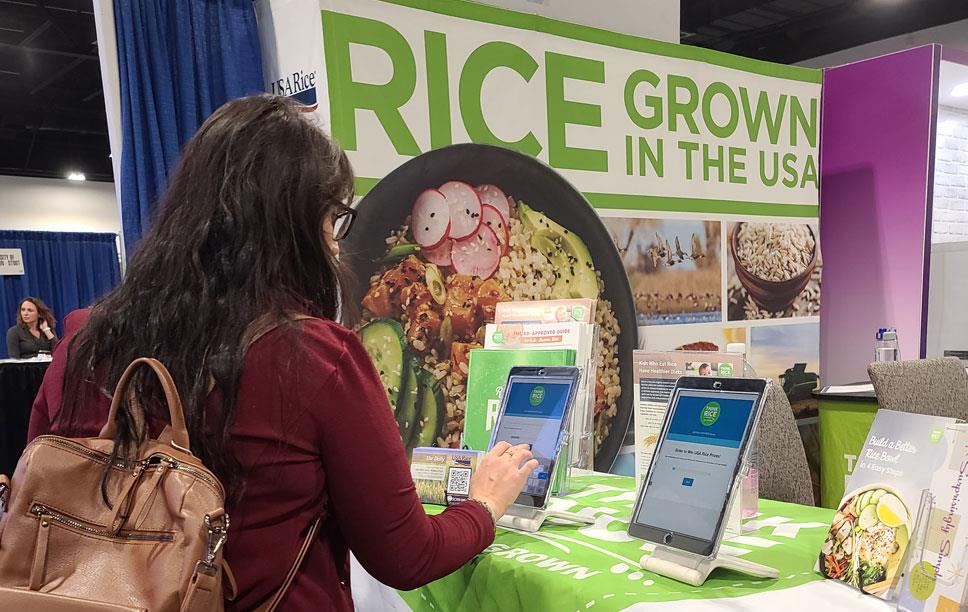 2023-FNCE,-woman-filling-out-USAR-survey with Rice Grown In The USA poster in background