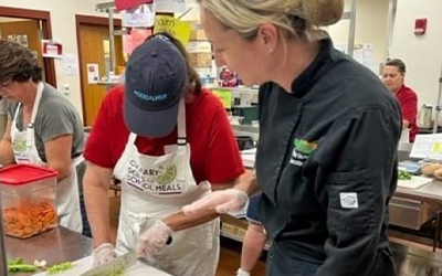 K-12 Training Session in school kitchen with instructor and student chef cutting veggies