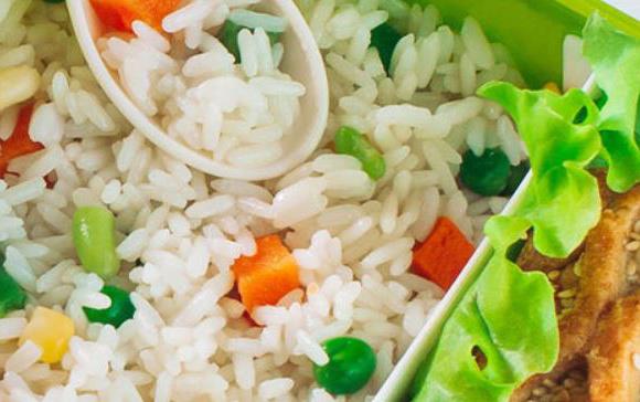Aerial view of colorful rice salad in green bowl w/white spoon