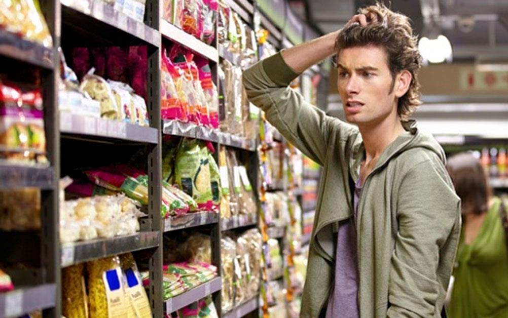 Confused shopper standing in rice aisle, scratching head