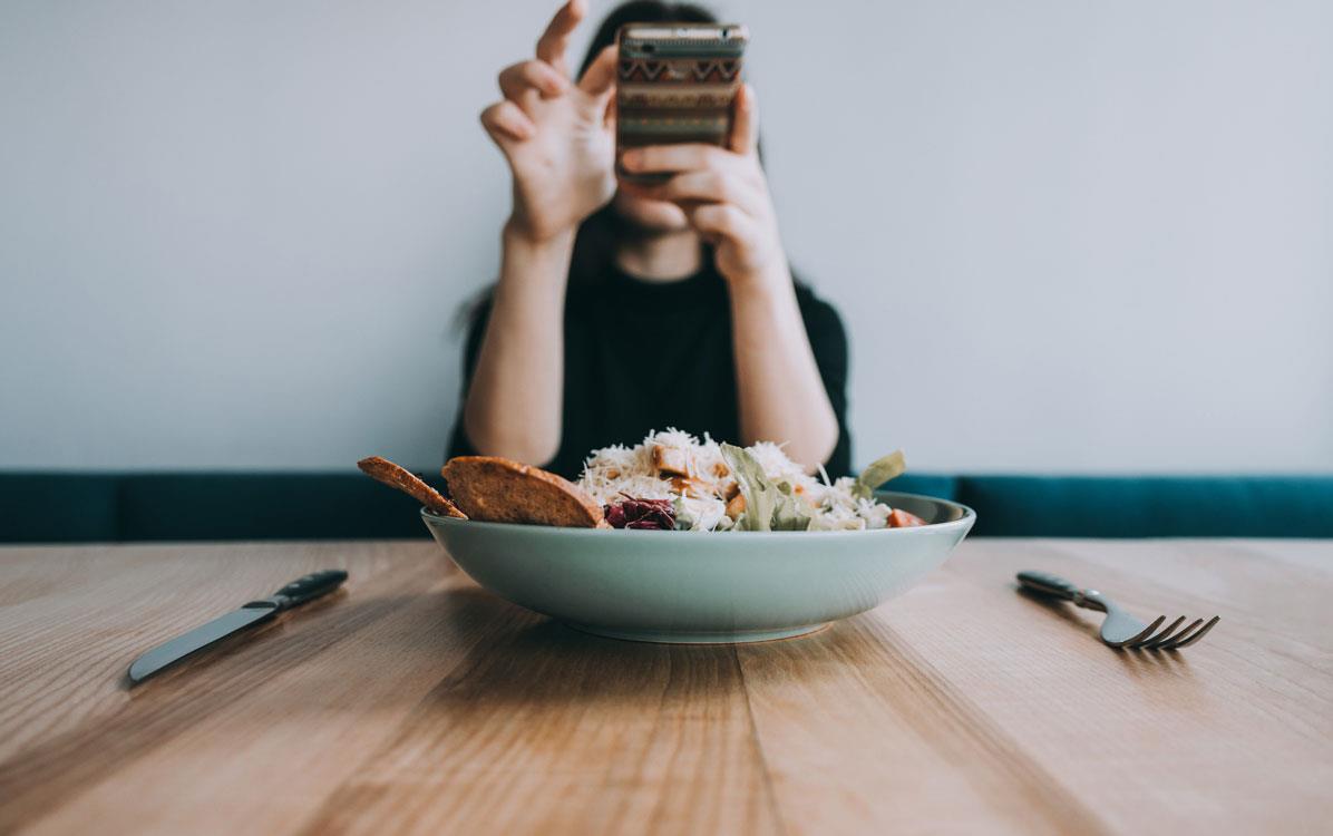 Social-Media-Food-Influencer takes photo on cellphone of rice bowl & utensils
