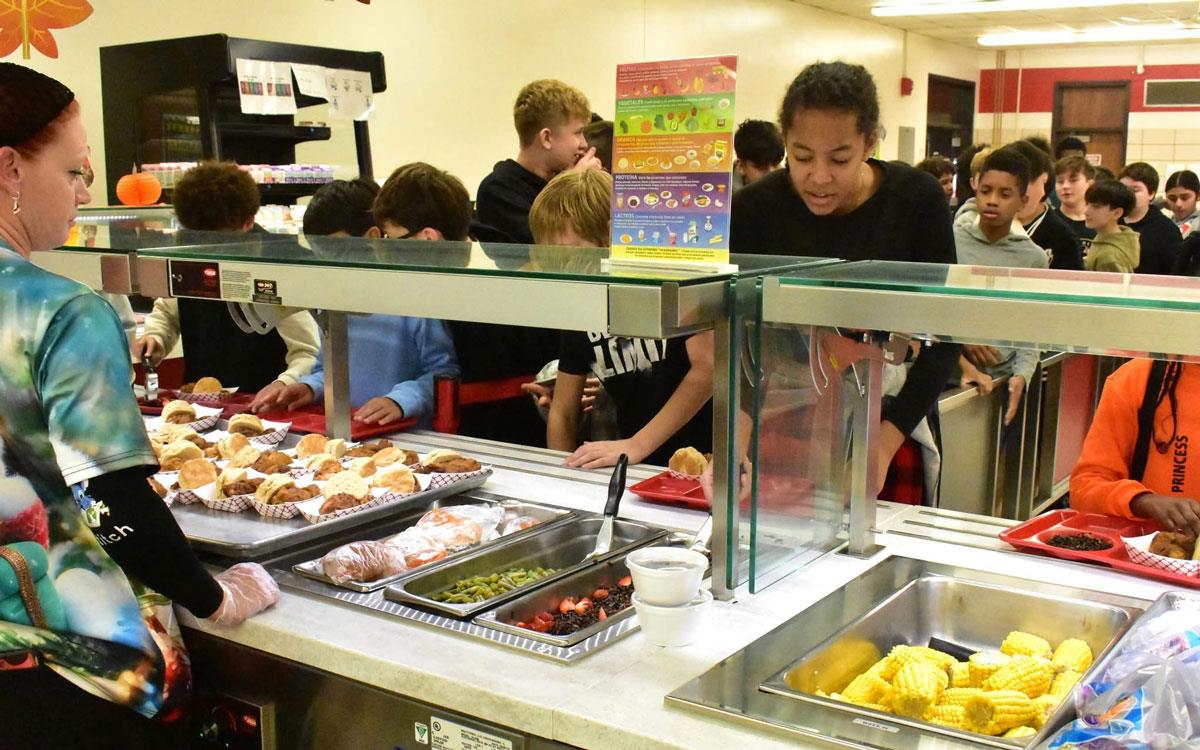 Students in school cafeteria line choosing from colorful food options