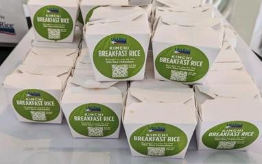 USAR Kimchi Breakfast Rice in takeout boxes with green labeling