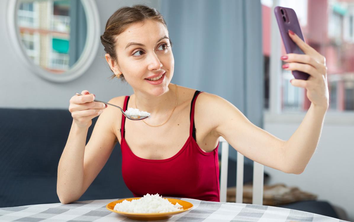 Young-woman-taking-selfie-while-eating-rice