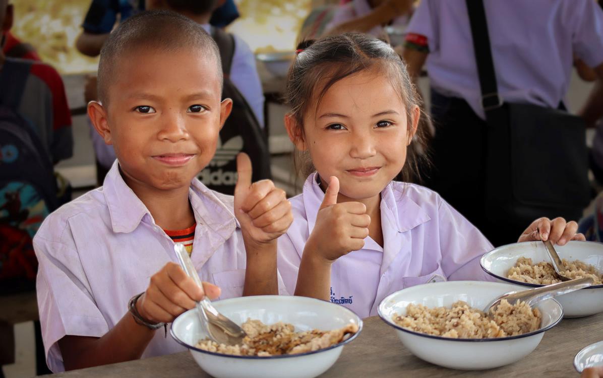 Two children eating rice give the thumbs up