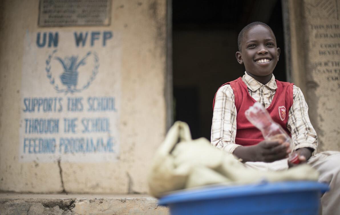 School boy sits in front of WFP signage