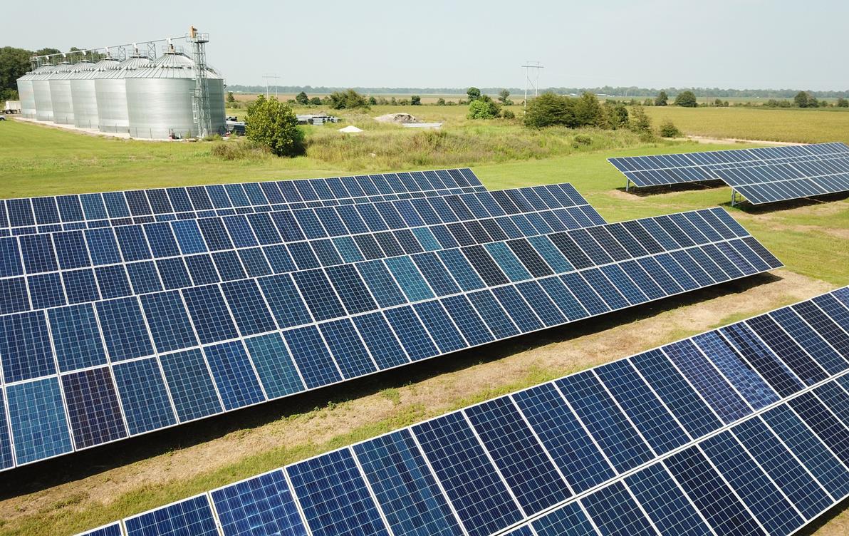 Solar panels in foreground, grain bins in background