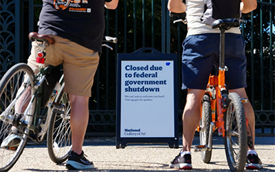Two bikers pause before Govt Shutdown signage, photo by Aaron Schwartz for Reuters
