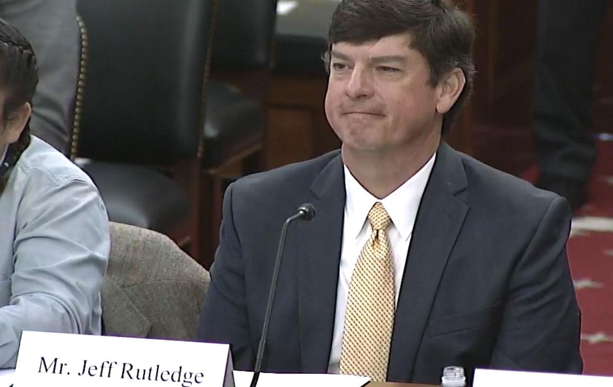 White man in business attire sits at table in front of ID: Mr. Jeff Rutledge