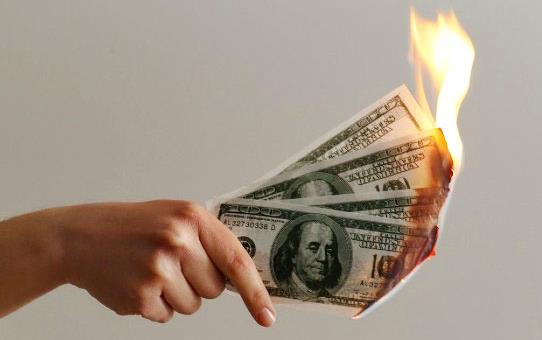 Hand holds $100 bills on fire