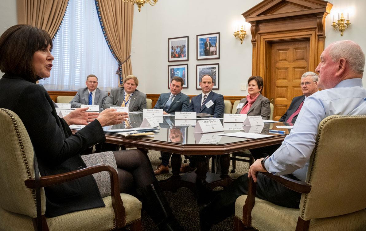 People dressed in business attire sit around large conference table