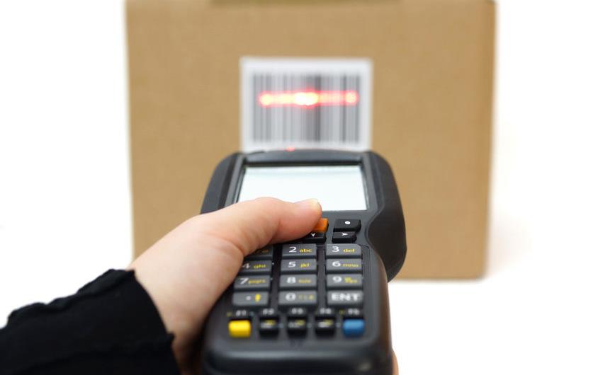 Hand holds scanner over QR codes on cardboard box