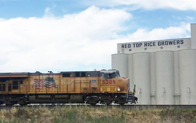 Train-with-US-Flag rolls by Red-Top-Rice-Growers-Mill in CA