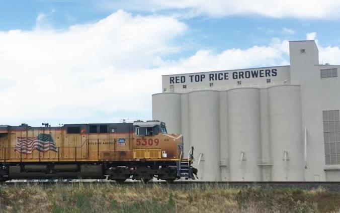 Train with US flag in front of Red Top Rice Growers Mill, M. Sligar photo