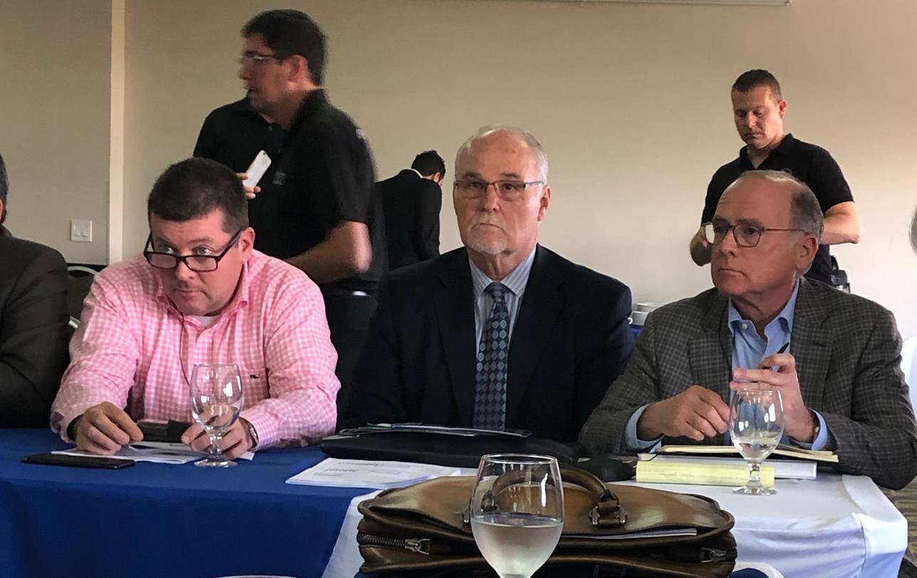 2019 Fecarroz mtg - people seated at table covered with blue tablecloth, glasses of water, paper, pens, and electronic devices