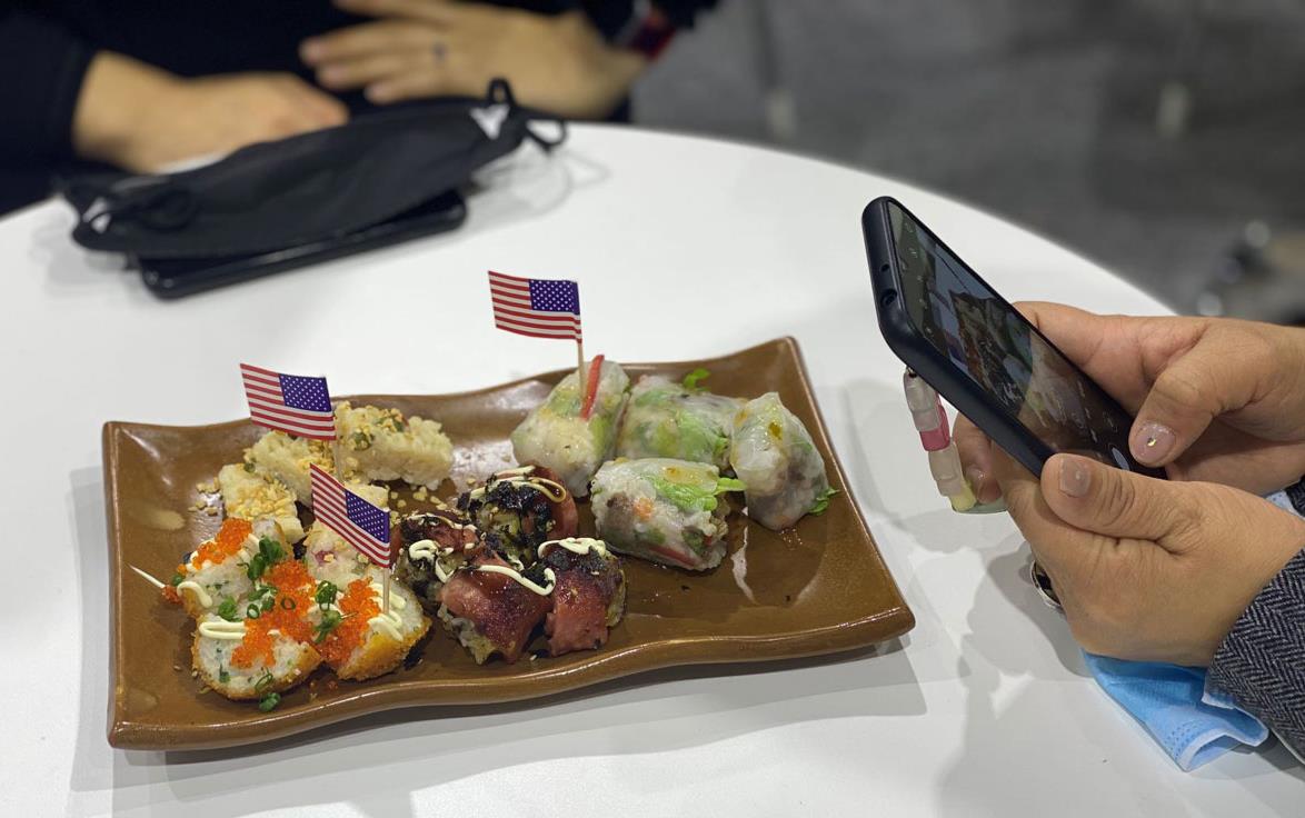 Rice samples on brown plate with American flags, hands holding phone taking photo to right