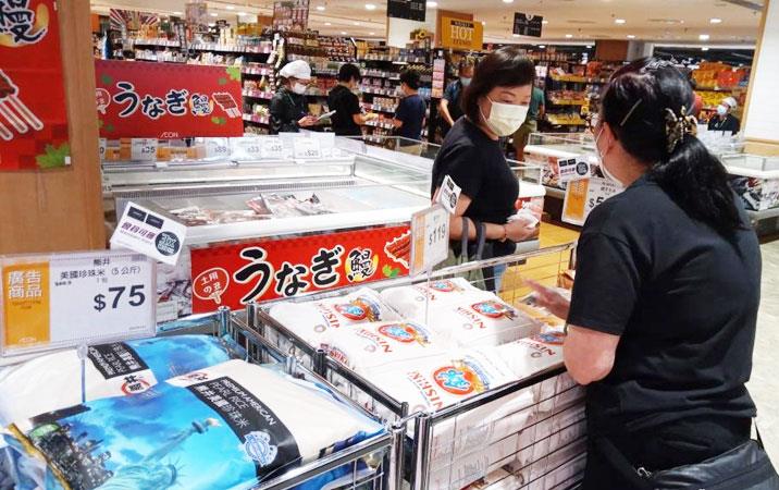 Women wearing face masks shop for rice in grocery store bins