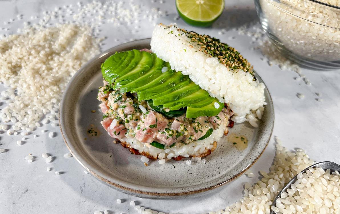 Tuna-Poke-Rice-Sandwich on plate surrounded by rice grains spilled on table