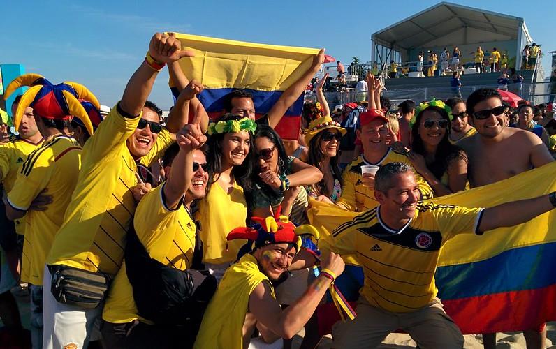Crowd of people wearing yellow shirts holding Colombian flags