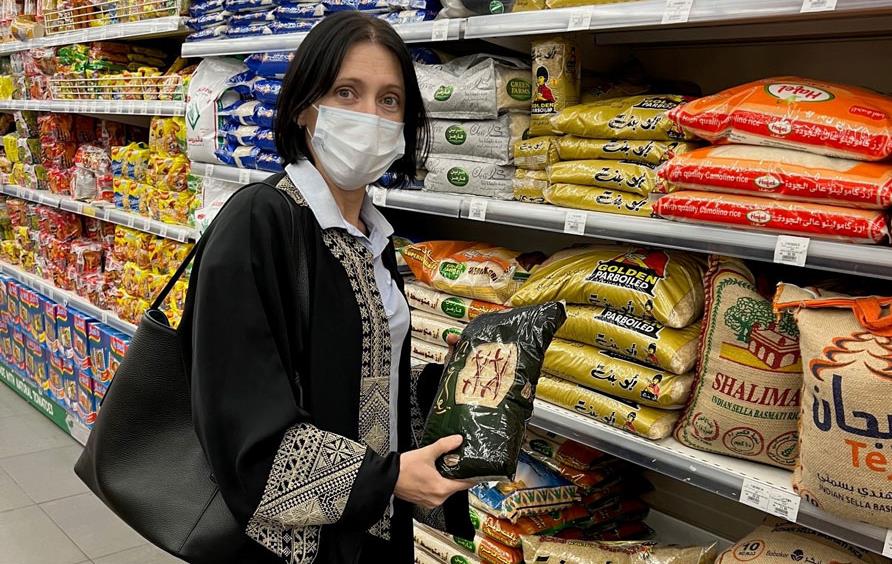 Woman with dark hair wearing a long, dark dress shops the rice aisle in Jeddah, Saudi Arabia