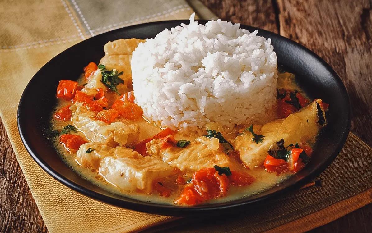 Ecuadoria dish - Pescado Encocado, fish stew with red peppers served with white rice on black plate