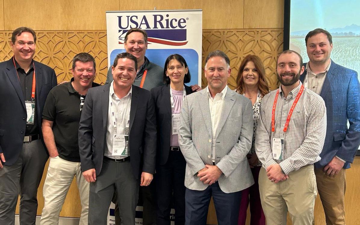 Gulfood-2024,-attendee-group-shot in front of USA Rice poster