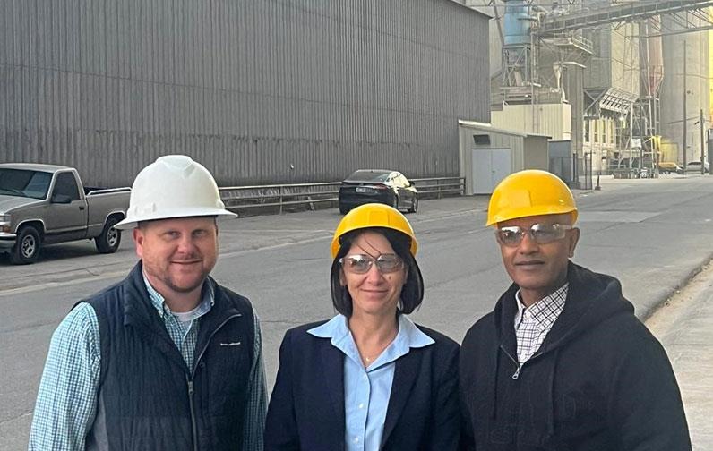 Three people wearing hard hats standing in front of Producers Rice Mill